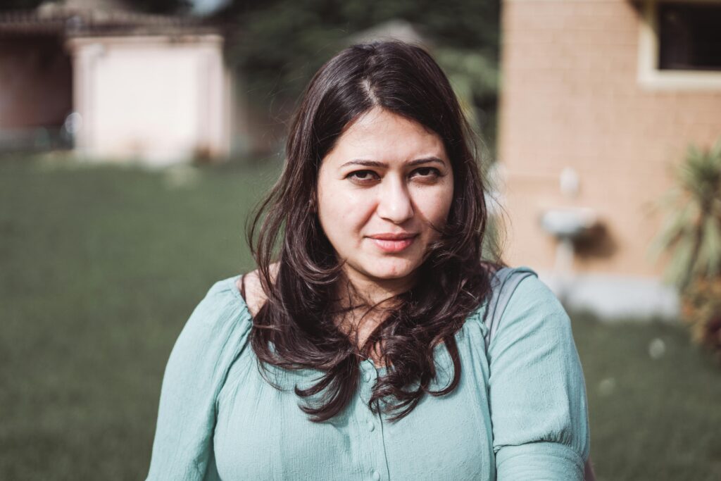A striking portrait of a woman with dark hair, captured outdoors in natural light.