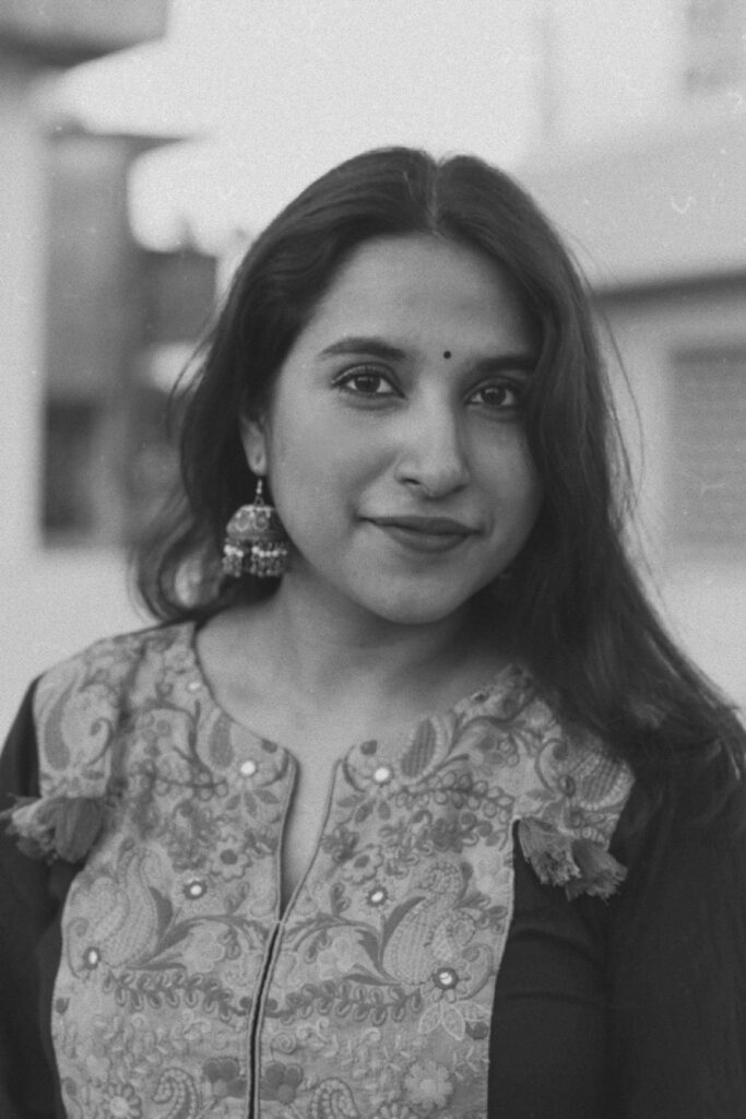 Black and white portrait of a smiling woman in Mumbai showcasing traditional jewelry and floral attire.